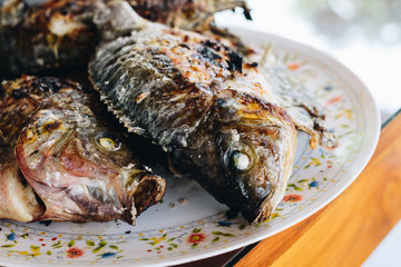 Grilled tilapia fishes on a plate. Selective focus.