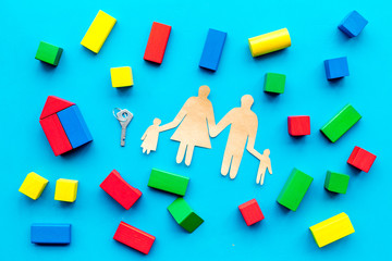 House building concept. Family cutout among colorful toy bricks on blue background top view