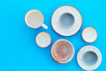 Kitchen concept. Crockery kit. Empty ceramic plates and mugs on blue background top view copy space