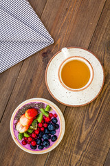 Light breakfast or healthy snack. Acai smoothie bowl with fresh fruits, berries, chia seeds on dark wooden background top view