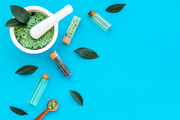 Make cosmetics with tea tree essential oil. Homemade cosmetics. Fresh tea tree leaves, mortar, cosmetics on blue background top view border copy space