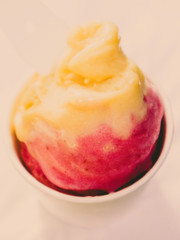 People holding a  Mango and Strawberry Ice Cream cone in a Summer Sunny Day with Green Background