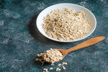 oatmeal in white plate on blue background and wooden spoon