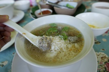 Rice porridge with parboiled egg, minced pork and pepper on the table, rice gruel or congee in restaurant, in the morning