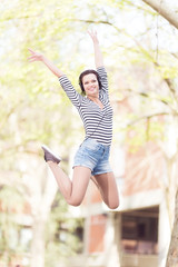 Young student jumping in front of a camera outdoors