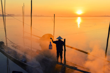 Asian fishermen hold fishing equipment on their boats to wait for fish in the Mekong River. In the...