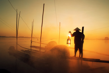 Asian fishermen hold fishing equipment on their boats to wait for fish in the Mekong River. In the morning of the new day