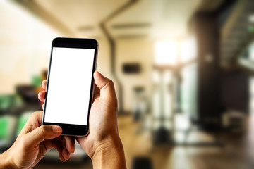 Hand holding white mobile phone with blank white screen  in gym.