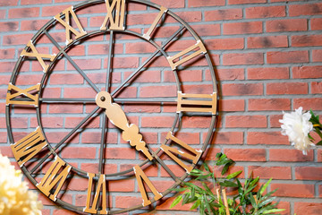 Brown, decorative clock with wooden figures hanging on a brown, brick wall.