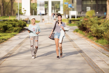 Young happy students walking outdoors in campus