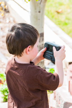 Little boy taking pictures with an old camera