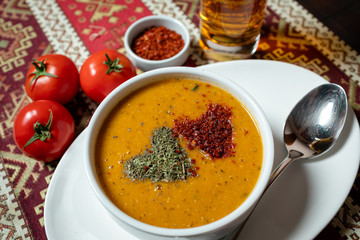Lentil soup with spices in a white bowl with a spoon on a white plate.On the table with a...