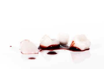 Blutige Zähne und Bluttropfen vor weißem Hintergrund