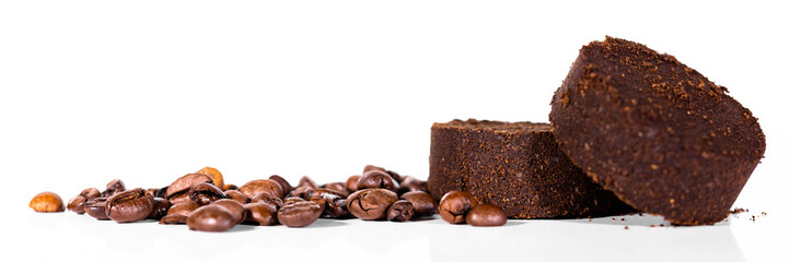 Panorama mit Kaffeebohnen und rund gepresster Kaffeesatz vor weißem Hintergrund