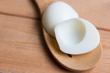 Peeling boiled egg on wooden spoon 