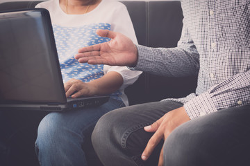 Man and woman workmate in casual dress discussing together while using laptop.