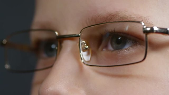 Extreme close up shot of eyes of young primary school boy putting on eyeglasses and looking at distance