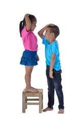 Obraz premium Little boy and girl measuring their height isolated on white background