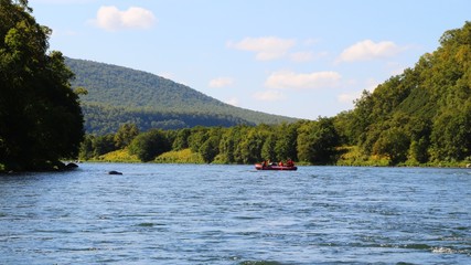 View of Bystraya Malkinskaya river on the Kamchatka Peninsula, Russia. Tourists on orange raft are visible on water.