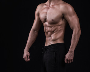 Fototapeta na wymiar Fit young man's torso. Muscular torso of slim fitness sporty man. Studio lighting, dark background