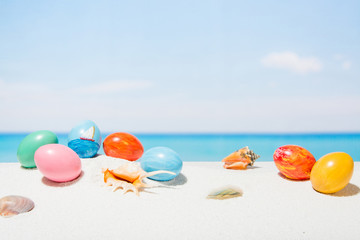 Obraz premium Easter on tropical beach background. Eggs on the white sand. Vacation and travel concept in spring