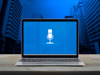 Microphone flat icon with modern laptop computer on wooden table over office city tower and skyscraper, Business communication online concept