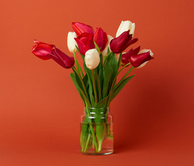 tulip flowers are in a vase on brown background