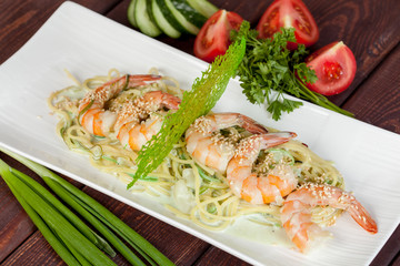  large and appetizing ready-made shrimps beautifully laid out with greens and vegetables for design solutions in cooking
