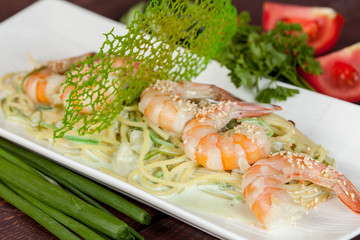  large and appetizing ready-made shrimps beautifully laid out with greens and vegetables for design solutions in cooking