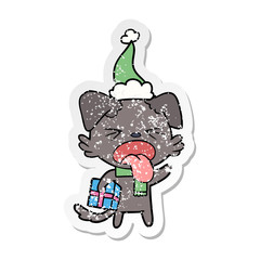 distressed sticker cartoon of a disgusted dog with christmas gift wearing santa hat