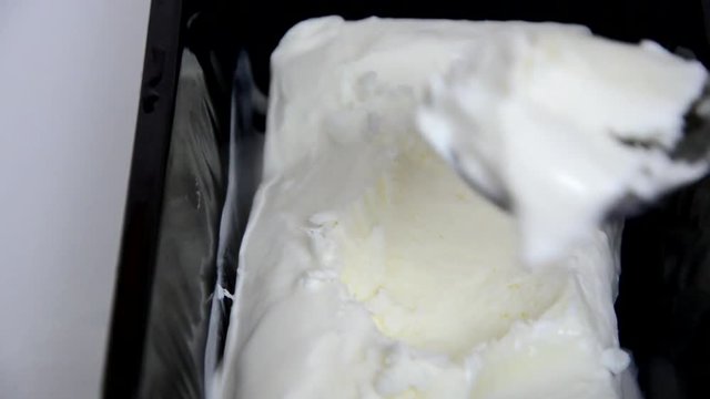 Vanilla ice cream Flat lay. Top view. Spoon for ice cream takes a little out of the package. Macking ball of ice cream.