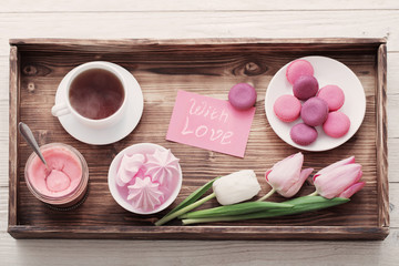 Tulips and cup of coffee with dessert on white background. Concept woman's or mother's day top view