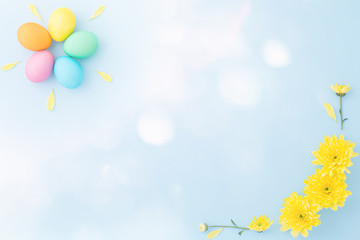 Colorful Easter eggs with springtime yellow flowers on a light blue background. Flat lay. Top view. Copy space