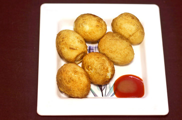 Boiled and fried whole eggs with red sauce in white plate on dark background