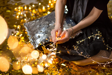 Amazing cute lady celebrating new year birthday party, posing in gold shine background and throwing colorful confetti with silver baloons.