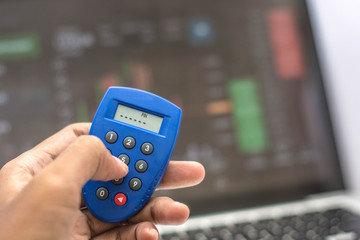 hand holding phone and internet security key and atm card with monitor showing internet transaction as background