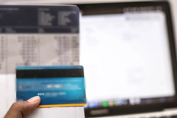 hand holding credit card and bank account with monitor showing e commerce, online transaction