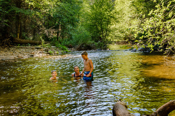 Mother with two children taking a bath in a small river in the forest - in Stanislaus National Park