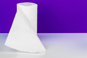 Roll of paper towel on table against purple background