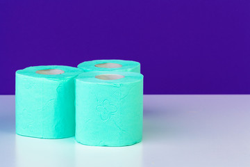 Toiletries. Rolls of green toilet paper on purple background