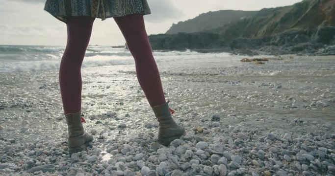 The legs of a young woman standing on the beach in winter