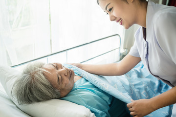 Asian nurse in elderly care cover her with a blanket for the elderly in nursing home.