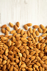 Almonds on a white wooden table, top view. Copy space.