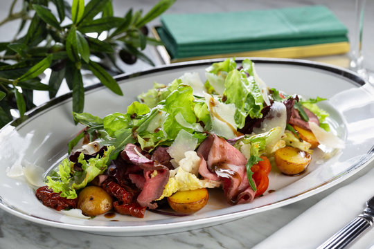 Salad with roast beef, potatoes, dried tomatoes, lettuce