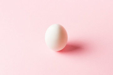 White Chicken Egg on a pink background. Minimalism. Side view