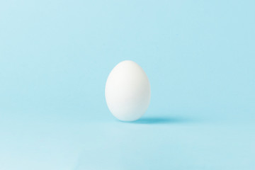 White Chicken Egg on a blue background. Minimalism. Side view