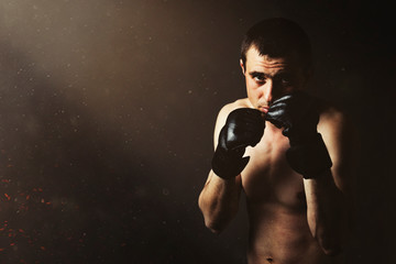 Fototapeta na wymiar A man in gloves for fighting without rules MMA on a black background. Workout concept, combat training