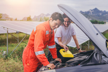 Technician checking car machine problem for female customer at outdoor. outdoor service concept