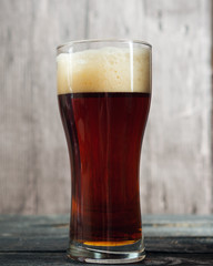 A glass of dark beer on a wooden table