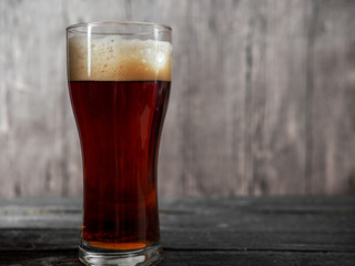 A glass of dark beer on a wooden table